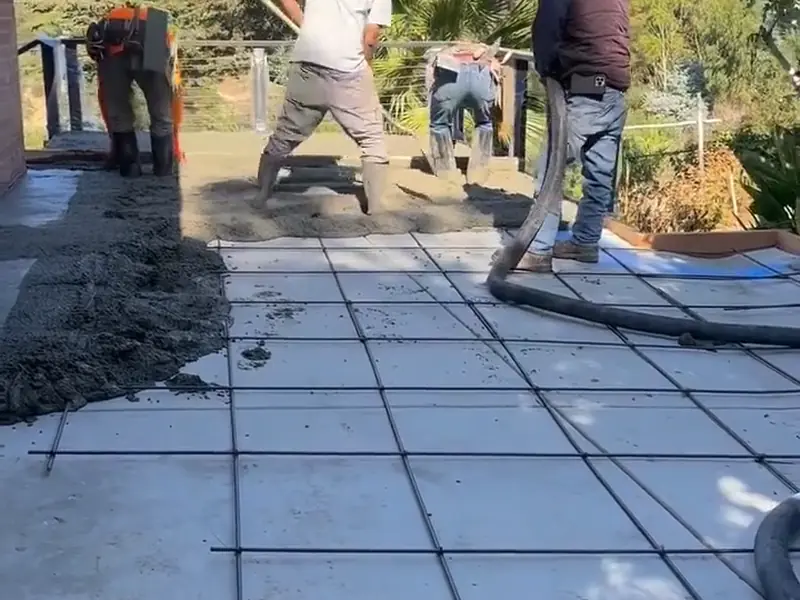 Crew pouring concrete over a rebar grid